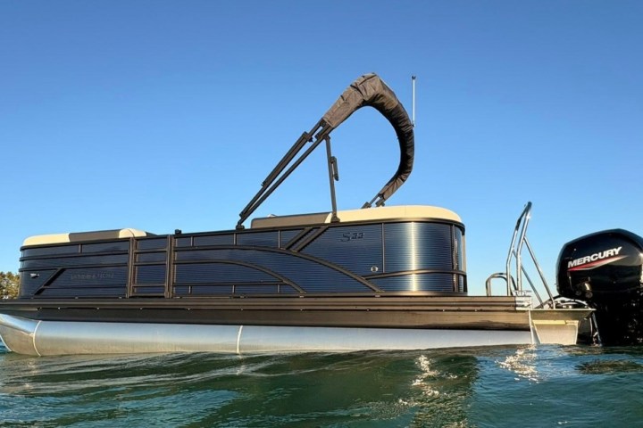 Pontoon boat with a Mercury motor on a calm lake.