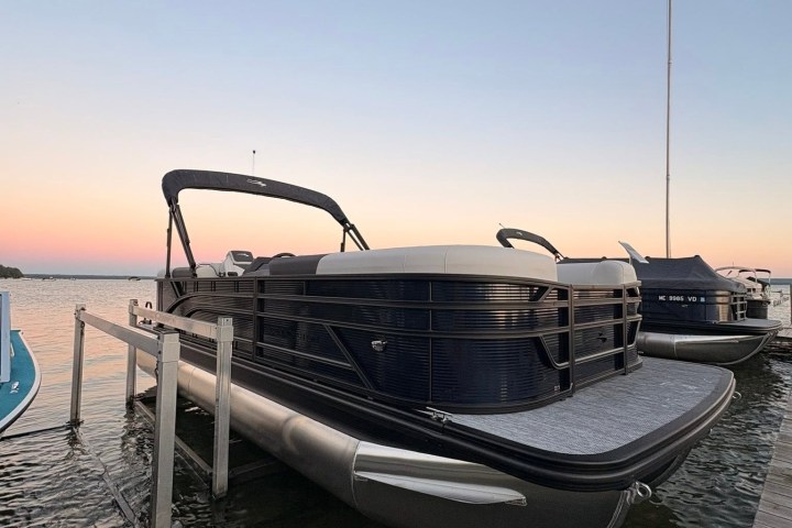 Pontoon boat docked at sunset with calm water.